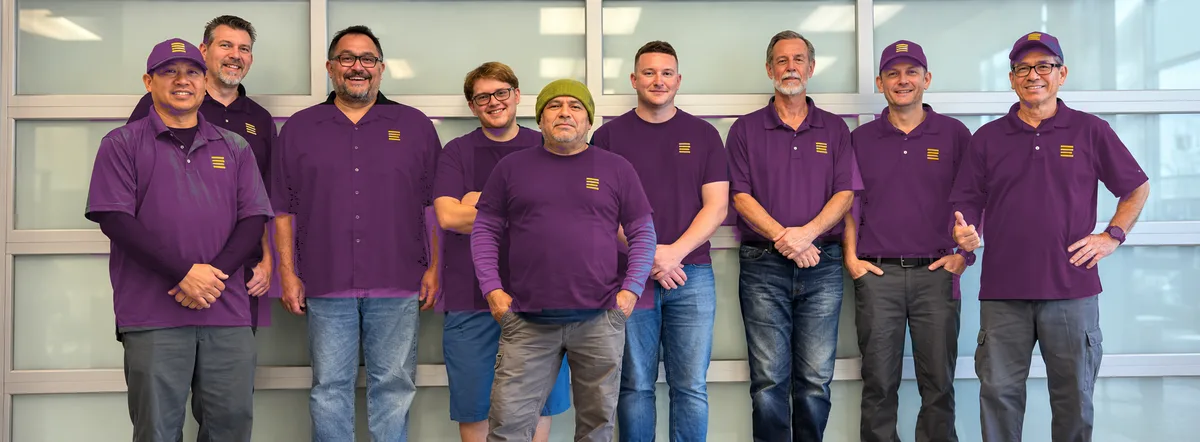 The Good Enough Garage Doors team of nine standing together in front of a glass garage door