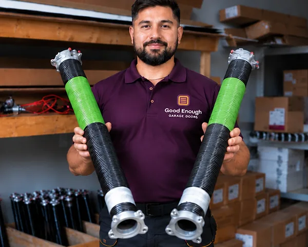 Good Enough Garage Doors technician holding two high-cycle torsion springs
